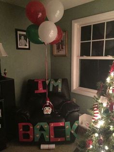 a decorated christmas tree in a living room next to a window with balloons on it