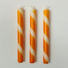 three orange and white candles sitting next to each other