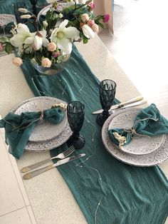 the table is set with silverware and green napkins, along with white flowers