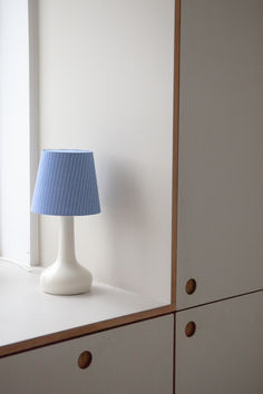 a blue lamp sitting on top of a white dresser