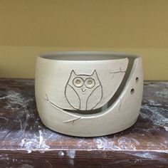 a ceramic bowl with an owl design on the front and bottom, sitting on top of a wooden table