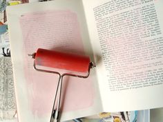 a red paint roller sitting on top of an open book