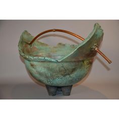 a large metal bowl sitting on top of a white table next to a wooden stick