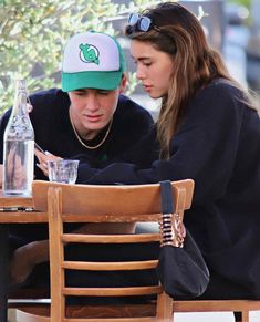 a man and woman sitting at a table looking at their cell phones