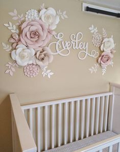 a crib with flowers on the wall next to a baby's name sign