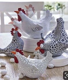 four ceramic chickens sitting on top of a wooden table