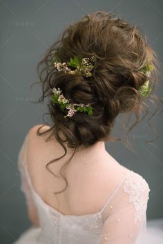 the back of a woman's head with flowers in her hair, wearing a white dress