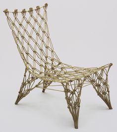 a chair that is made out of wire and has an intricate design on the back