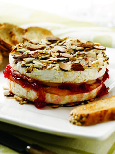 there is a sandwich on the plate with fruit and nuts next to some crackers