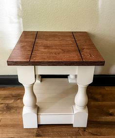 a wooden table with white legs and a brown top on a hard wood floor next to a wall