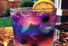 a glass filled with ice and lemon sitting on top of a table