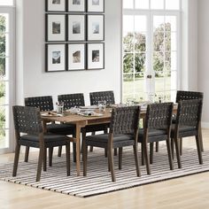 a dining room table with chairs and pictures on the wall above it in front of a window