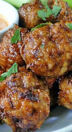 some meatballs are sitting on a plate with dipping sauce