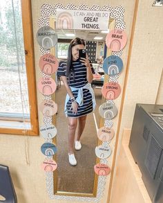 a woman taking a selfie in front of a mirror with words all over it