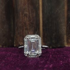 an emerald cut diamond ring on purple velvet