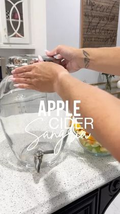 a woman is using her cell phone on the kitchen counter with an apple bowl and salad in it