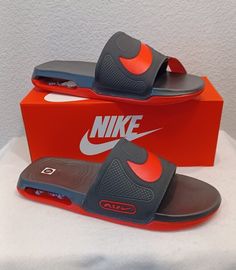 a pair of grey and orange sandals sitting in front of a red box with the word nike on it