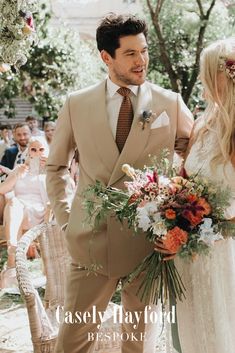 a man in a suit and tie holding a bouquet next to a woman wearing a wedding dress