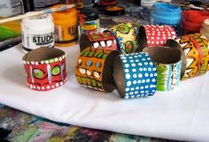 several colorful cupcakes sitting on top of a white tablecloth covered in paint