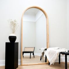 a large mirror sitting on top of a wooden floor next to a black table and chair