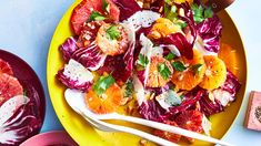 a yellow plate topped with salad next to two pink plates filled with oranges and radishes