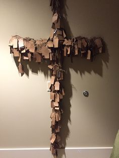 a cross made out of brown paper hanging on the wall