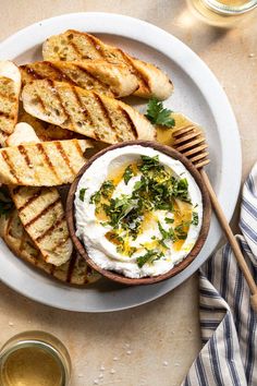 a white plate topped with grilled bread and anchovies next to a glass of beer