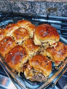 a glass baking dish filled with sliders on top of an oven burner next to a granite counter