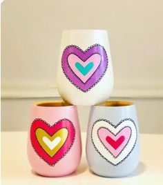 three colorful cups with hearts painted on them