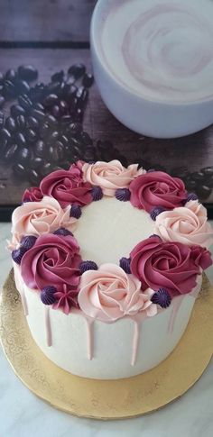 a white cake with pink and purple flowers sitting on top of a gold platter