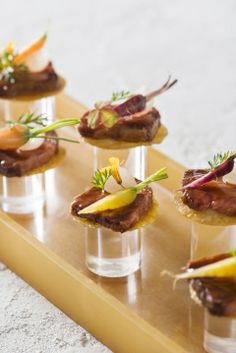 small appetizers are arranged on a wooden platter with garnishes