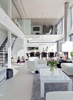 a living room filled with white furniture and lots of windows next to a stair case