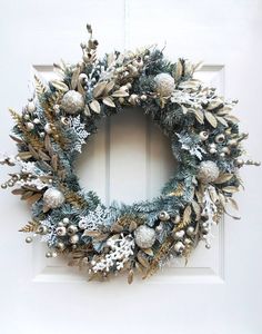 a wreath is hanging on the front door with silver balls and greenery around it