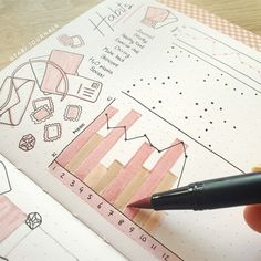 a person is holding a pen and drawing on some paper with graphing tools next to it