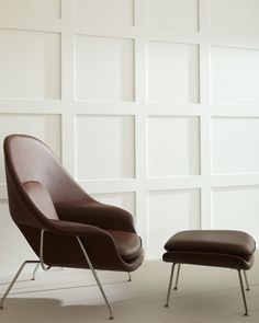 an egg chair and ottoman in front of a white wall