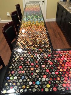 a long table covered in lots of different colored bottle caps on top of a wooden floor