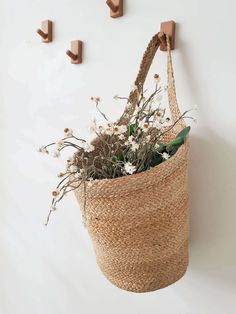 a basket hanging on the wall with flowers in it and two hooks attached to it