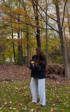 a woman standing in the grass with leaves on her feet