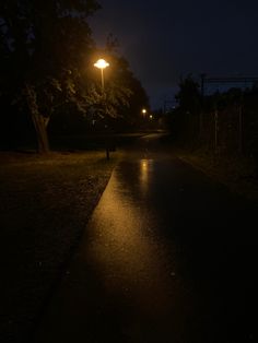 a dark street at night with the light on and one person standing in the rain