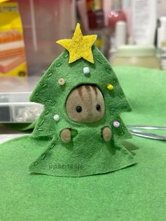 a small green christmas tree with a star on it's head, sitting on top of a table