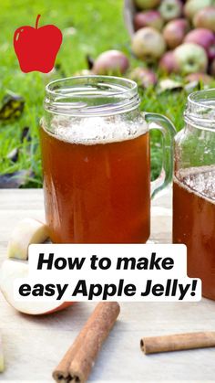 two jars filled with apple cider sitting on top of a table next to apples