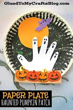 a paper plate with halloween decorations and ghost hands on it, in front of a white background