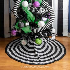 a black and white christmas tree decorated with green, purple, and silver ornaments on top