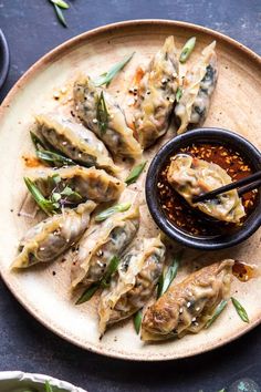 a plate with some dumplings and dipping sauce on it next to chopsticks