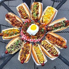 hot dogs with toppings arranged in a circle on top of a metal grill grate