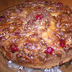 a cake with nuts and cranberries on it sitting on a glass platter