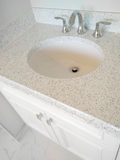 a bathroom sink with two faucets on the top and marble countertop above it