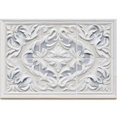 white tile with an intricate design in the center and bottom panel, on top of it