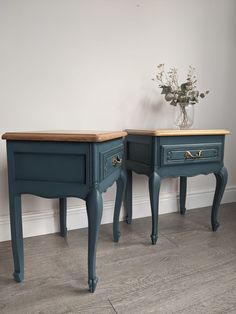 two blue nightstands side by side against a white wall with flowers in vase on top