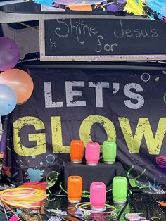 there is a sign that says let's glow with balloons and confetti